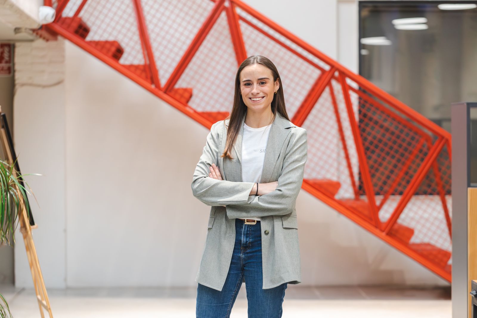 Claudia Cambra, fundadora de Silocomo, con los brazos cruzados junto a una escalera roja
